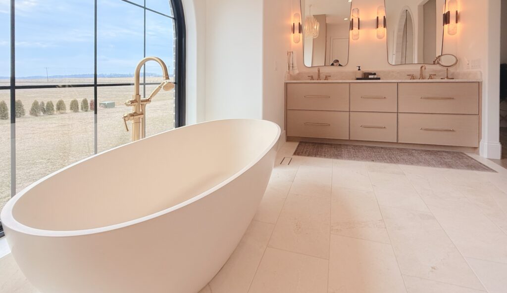 Primary bathroom with freestanding tub, arched window and floating white oak double vanity with brass pulls